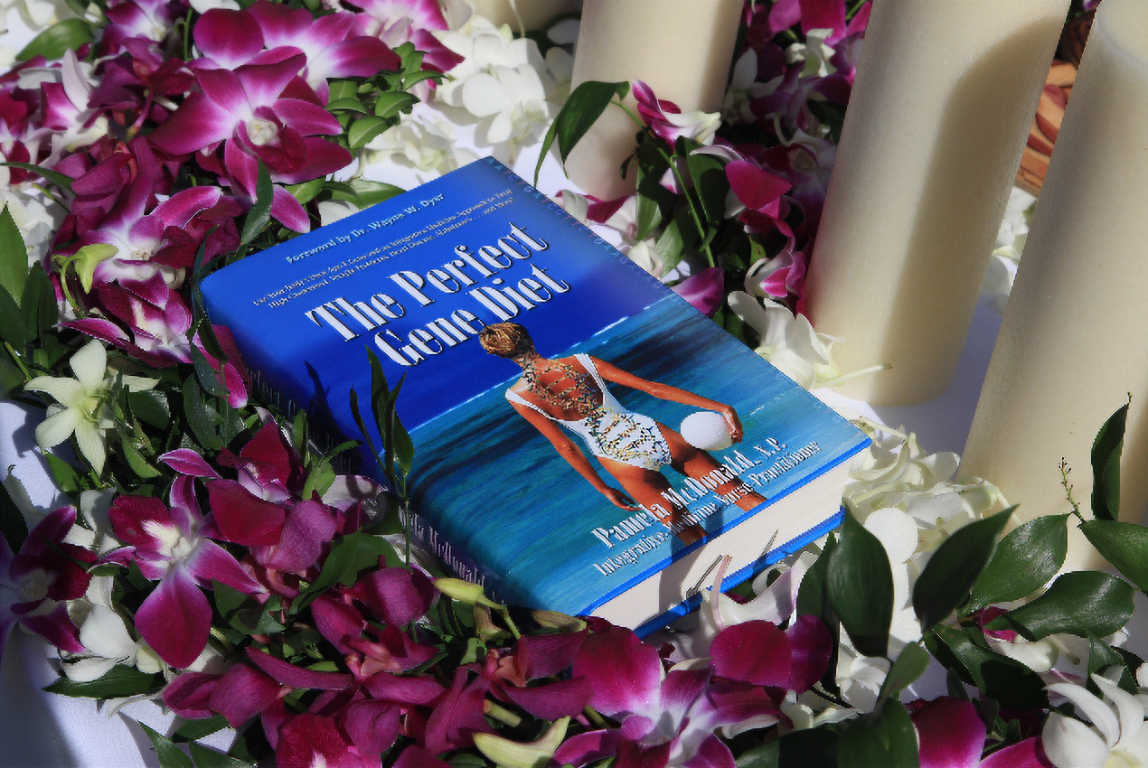 A book titled "the periodic table of feminism" surrounded by purple and white flowers and white candles.