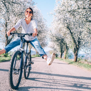 Woman riding bicycle with spring blossoms on trees in background