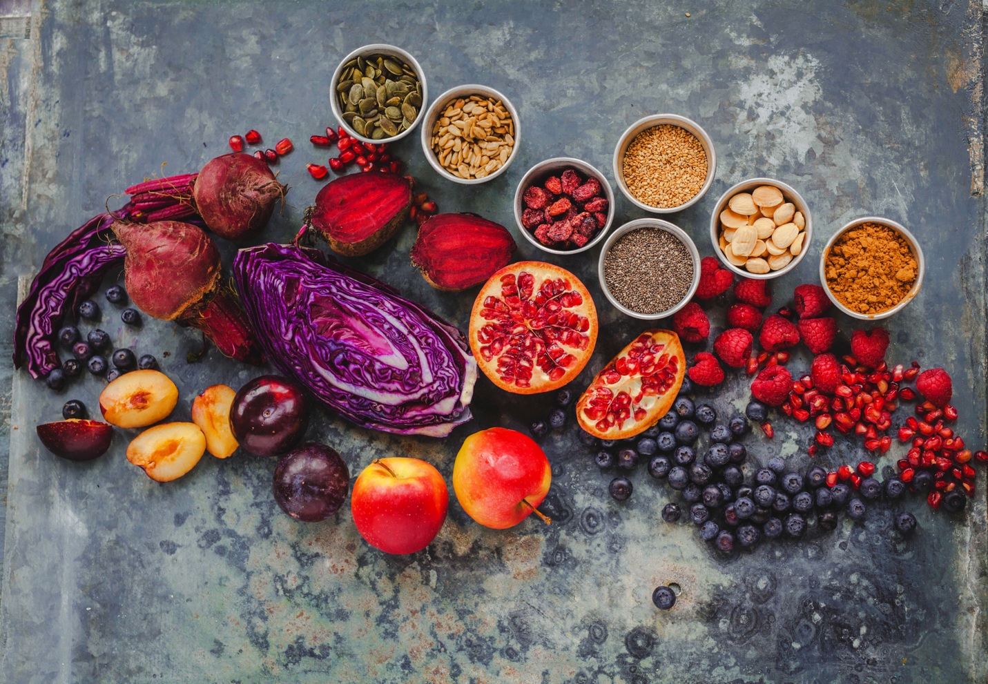 various fruits,vegetables, seeds, and nuts laid across a mottled table